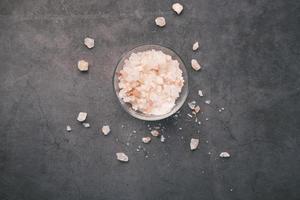 top view of pink rock salt in a bowl on black background photo