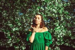 una niña está de pie en el parque debajo de un manzano en flor foto