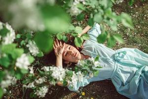 Girl lies in the park on the grass under a blooming apple tree photo