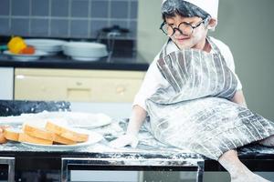 chico asiático llevar gafas molestar a papá cocinando foto