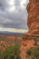 Woman standing on a cliff next to red rocks photo