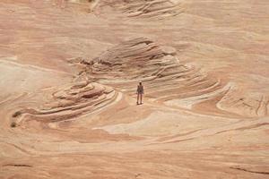 Mujer caminando sobre una formación rocosa de arenisca en el desierto foto