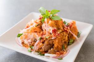 Spicy salad with fried chicken on the table photo