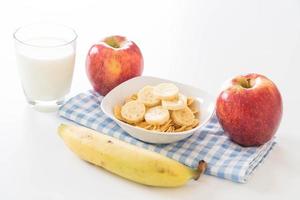 leche, manzana, plátano y copos de maíz para el desayuno foto