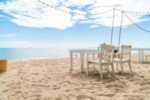 White chairs and table on beach with a view of blue ocean and clear sky photo