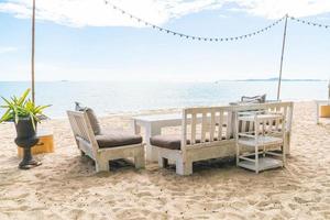 White chairs and table on beach with a view of blue ocean and clear sky photo