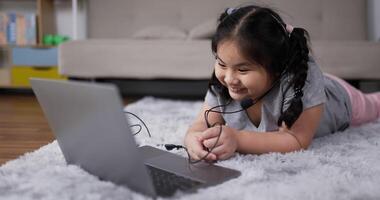 bambina che indossa le cuffie durante l'apprendimento online in soggiorno video