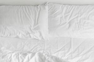 Cama con borde con decoración de almohada desordenada blanca en el interior del dormitorio foto