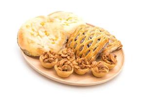 Tarta de toffee, pan con mahonesa de maíz y tartas de taro sobre fondo blanco. foto