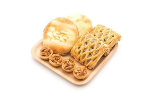 Tarta de toffee, pan con mahonesa de maíz y tartas de taro sobre fondo blanco. foto
