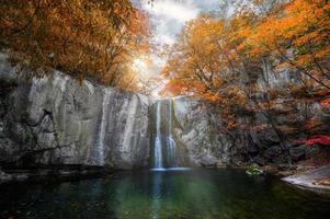 Waterfall flowing in autumn forest on national park photo