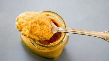 Mustard on spoon with blue background photo