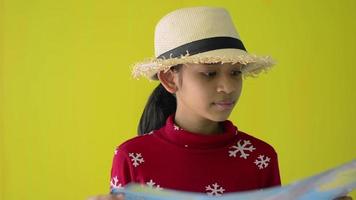 joven viajera lleva sombrero de paja mirando un mapa del mundo.