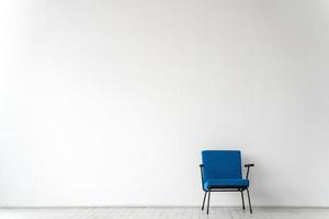 Habitación vacía con una silla azul sobre una pared blanca de fondo foto