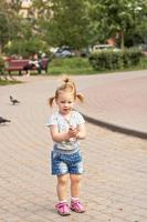 niña pequeña corre detrás de las palomas. Hora de verano foto