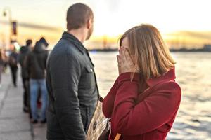 couple man and woman in a quarrel, on the embankment at sunset. photo