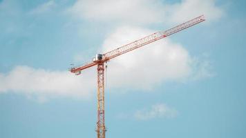 Grúa torre en el sitio de construcción sobre un cielo azul con nubes foto