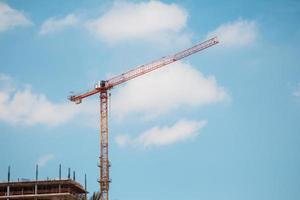 Tower crane in construction site over blue sky with clouds photo