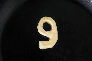 Mantequilla en forma de número 9 en sartén caliente - Vista superior de cerca