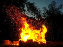 Sparks bounce off from a bonfire at night after a log thrown into it photo