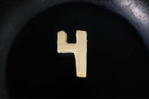 Butter in shape of number 4 on hot pan - Close up top view photo