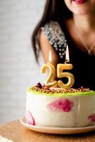 Mujer caucásica en traje de fiesta negro encendiendo velas en la tarta de cumpleaños foto