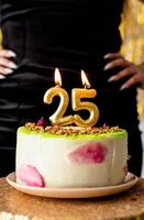 Velas encendidas de oro 25 en tarta de cumpleaños foto