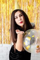 woman in birthday hat holding balloon on golden background photo