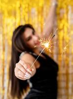 woman holding sparkler and balloon on golden background photo