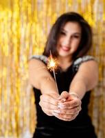 woman holding sparkler and balloon on golden background photo