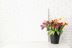 Mock up con bastidor y balde de tulipanes sobre fondo de pared de ladrillo blanco