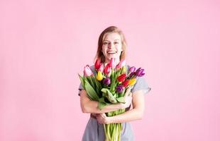 woman holding bouquet of fresh tulips isolated on pink background photo