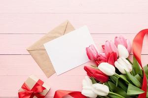 Tarjeta de felicitación y sobre con coloridos tulipanes de primavera vista superior foto