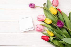 Top view of blank calendar with colorful tulips on white background photo