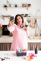 Beautiful woman taking selfie using mobile phone in the kitchen photo