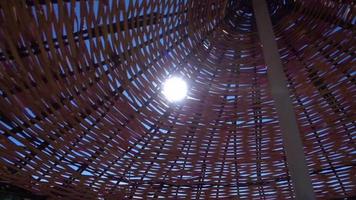 les rayons du soleil qui brillaient à travers les trous du parapluie en bois sur la plage entourée video