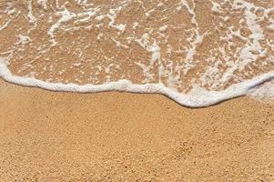 Playa de arena orilla del mar con olas y fondo de verano espumoso blanco