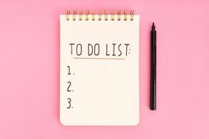 To do list in spiral notepad isolated on pink background. Top view photo