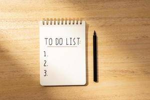 To do list in spiral notepad isolated on wooden desk. Flat lay photo