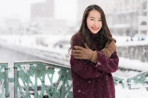 Mujer asiática sonriendo feliz para viajar en la temporada de invierno con nieve foto