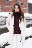 Mujer asiática sonriendo feliz para viajar en la temporada de invierno con nieve foto