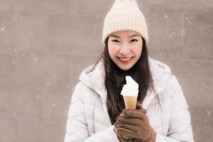 Young asian woman smile and happy with ice cream in snow winter season photo