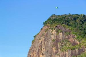 Helm Stone con la bandera de Brasil en la parte superior, visto desde la playa de Helm en Río de Janeiro, Brasil