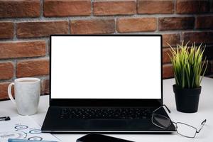 escritorio de trabajo con ordenador portátil de pantalla en blanco. foto