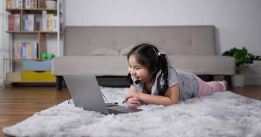 menina com fone de ouvido, aprendendo online na sala de estar video
