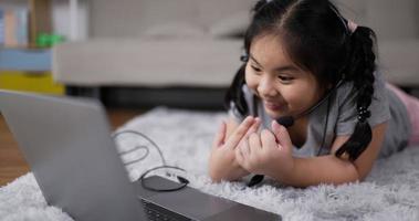 garota usando fone de ouvido durante o aprendizado on-line na sala de estar