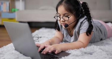 niña con auriculares durante el aprendizaje en línea en la sala de estar
