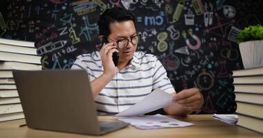 profesor hablando por teléfono móvil durante la verificación del informe video