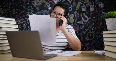 leraar die aan de telefoon praat tijdens het controleren van het rapportpapier video