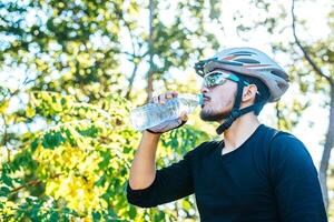 los ciclistas se paran en la cima de la montaña y beben una botella de agua. foto